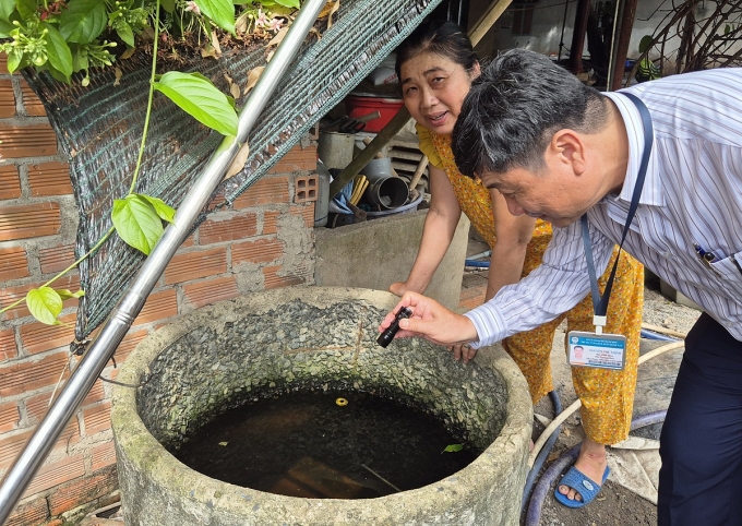 Cán bộ ngành y tế TP HCM soi đèn tìm loăng quăng ở các vật dụng chứa nước tại nhà dân khi giám sát phòng chống dịch ở Củ Chi, hồi tháng 7. Ảnh: Lê Phương