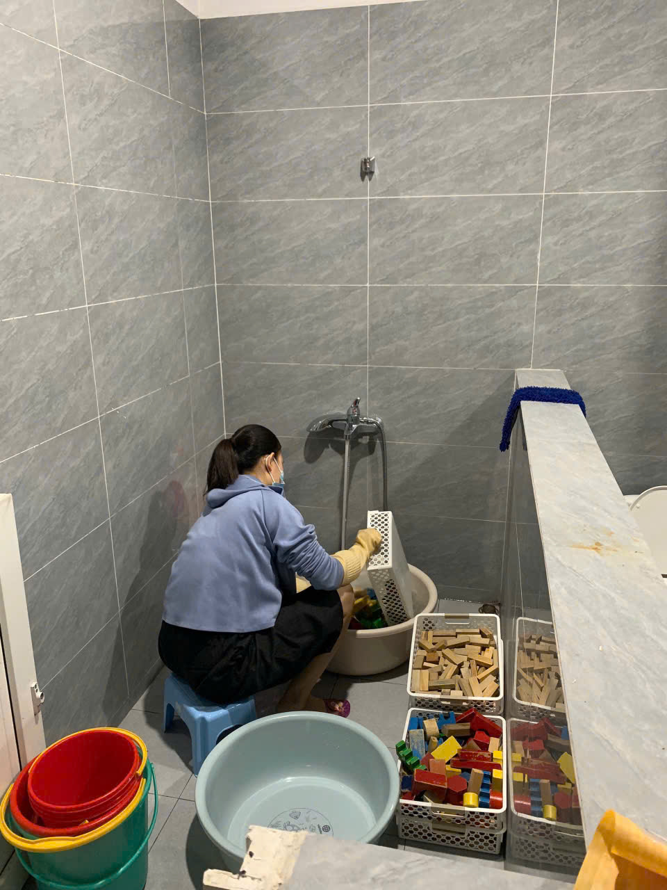 Cô giáo rửa và sấy khô đồ chơi tại trường mầm non, giảm nguy cơ lây nhiễm cúm A ở trẻ nhỏ.